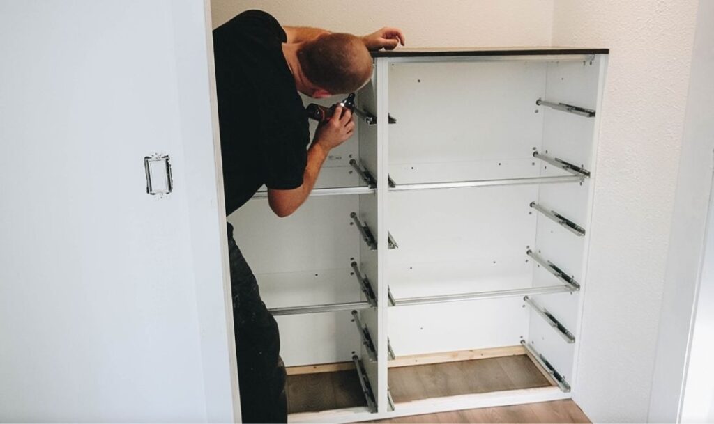 person building a dresser inside of a closet