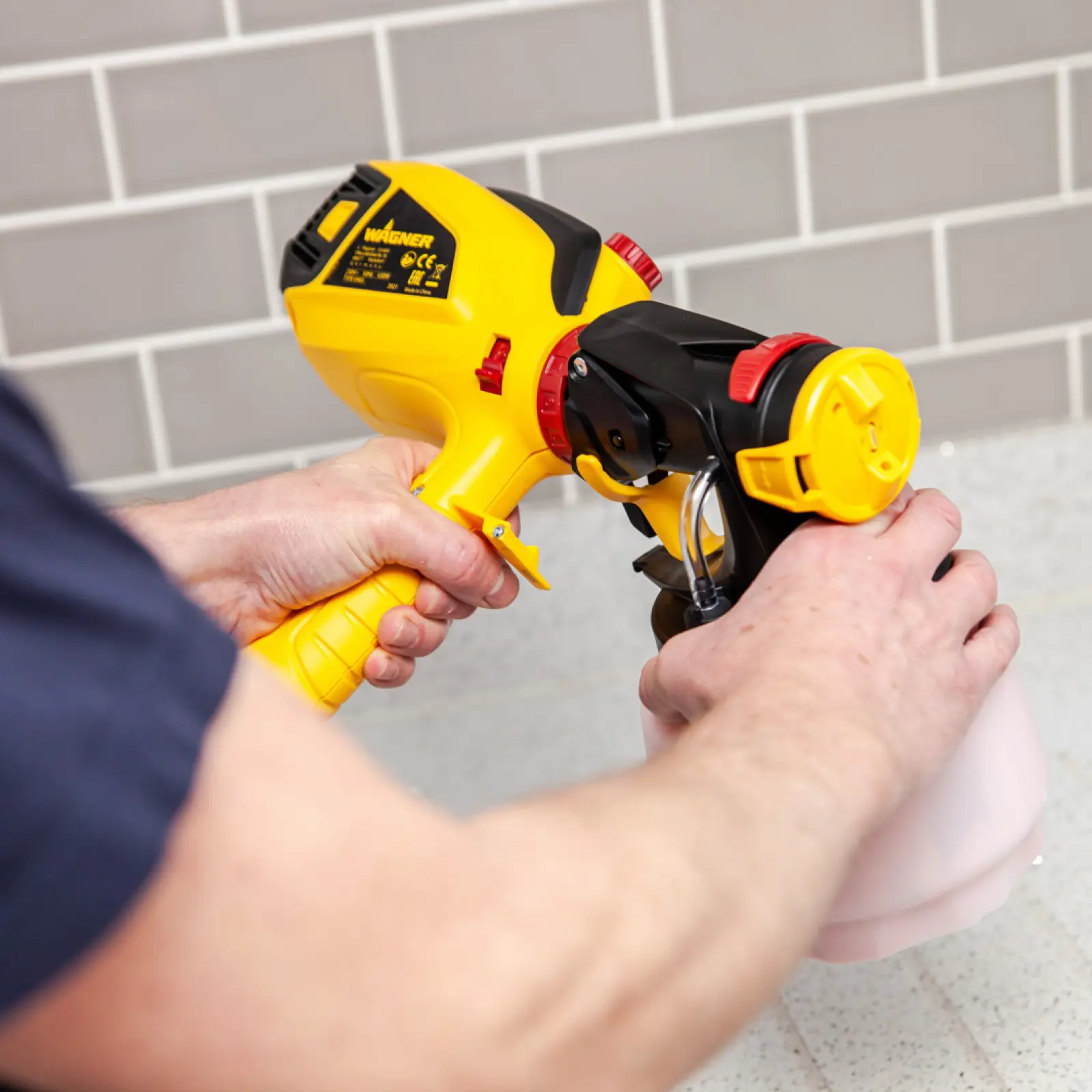 Handheld Wagner paint sprayer being assembled by a person.
