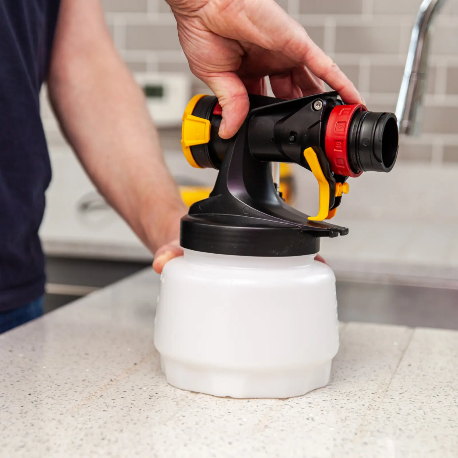 Hand assembling a black and yellow paint sprayer nozzle.