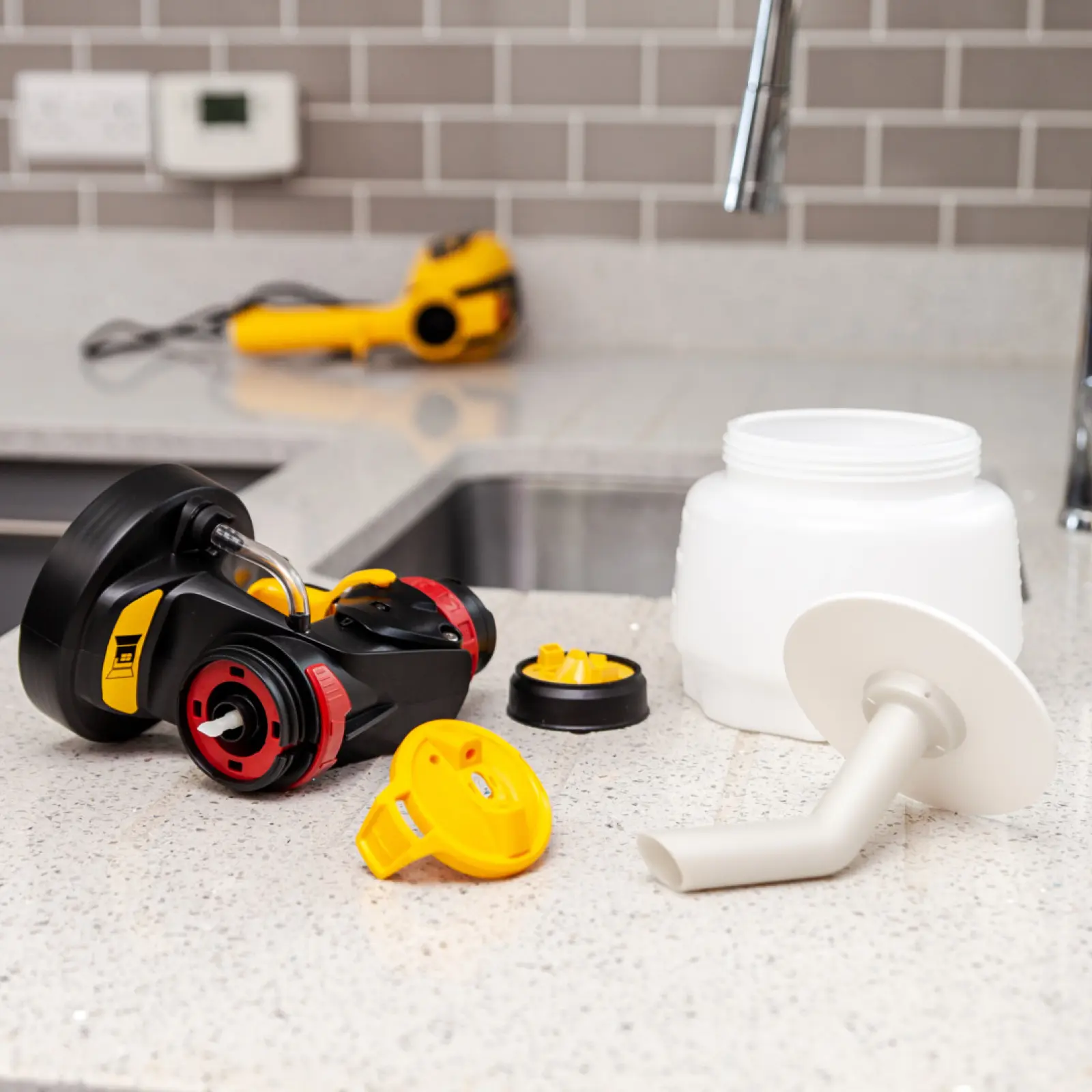 Disassembled paint sprayer parts on a kitchen countertop.