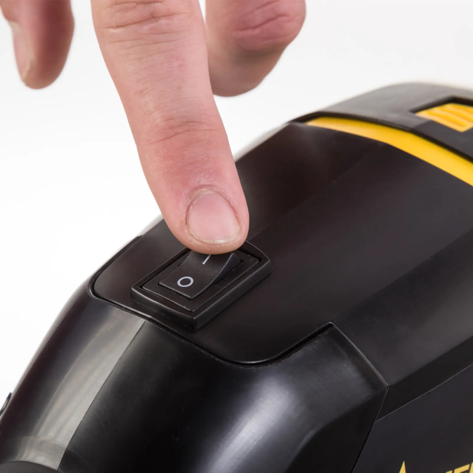 Finger pressing a power switch on a black power tool.
