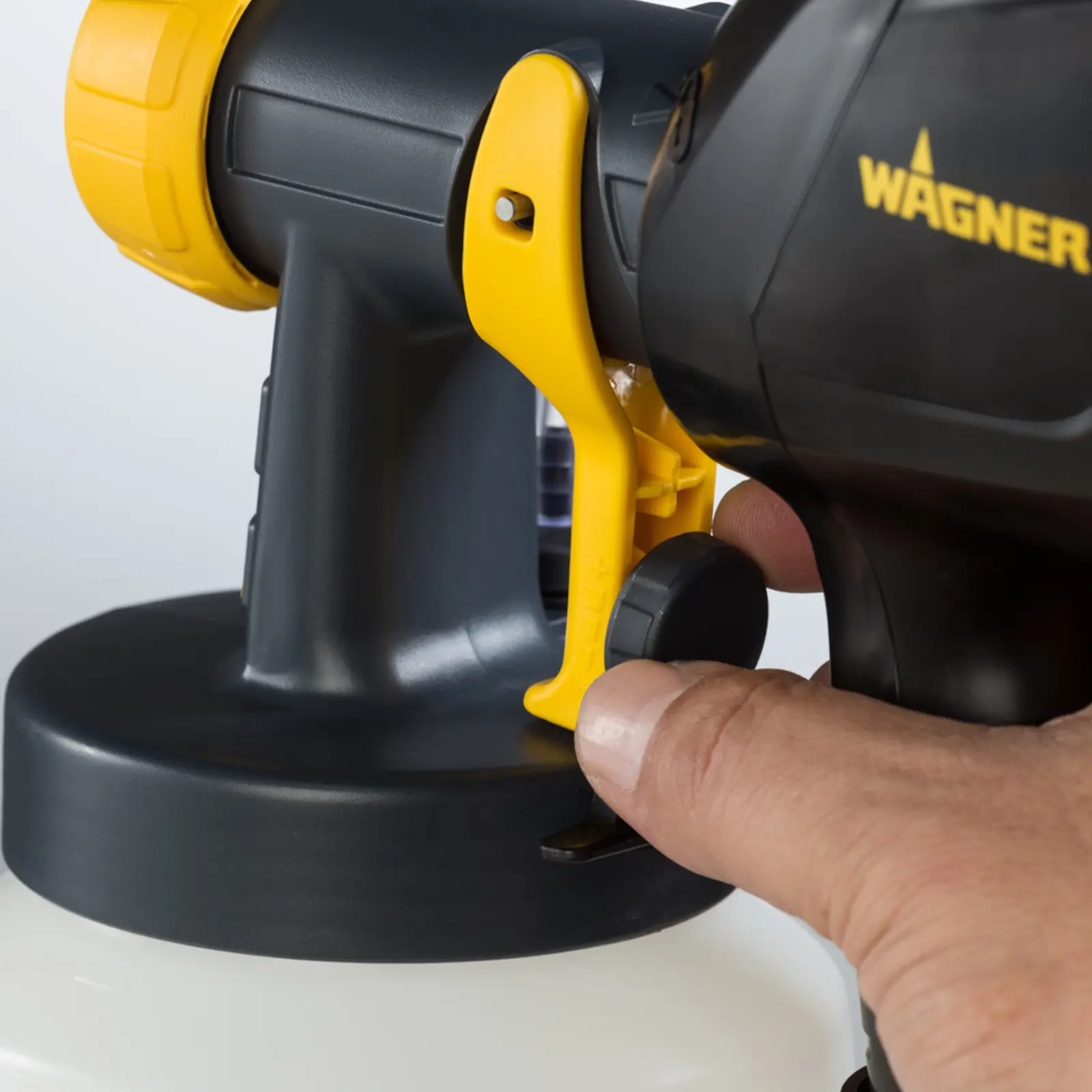 Hand adjusting the dial on a Wagner paint sprayer.