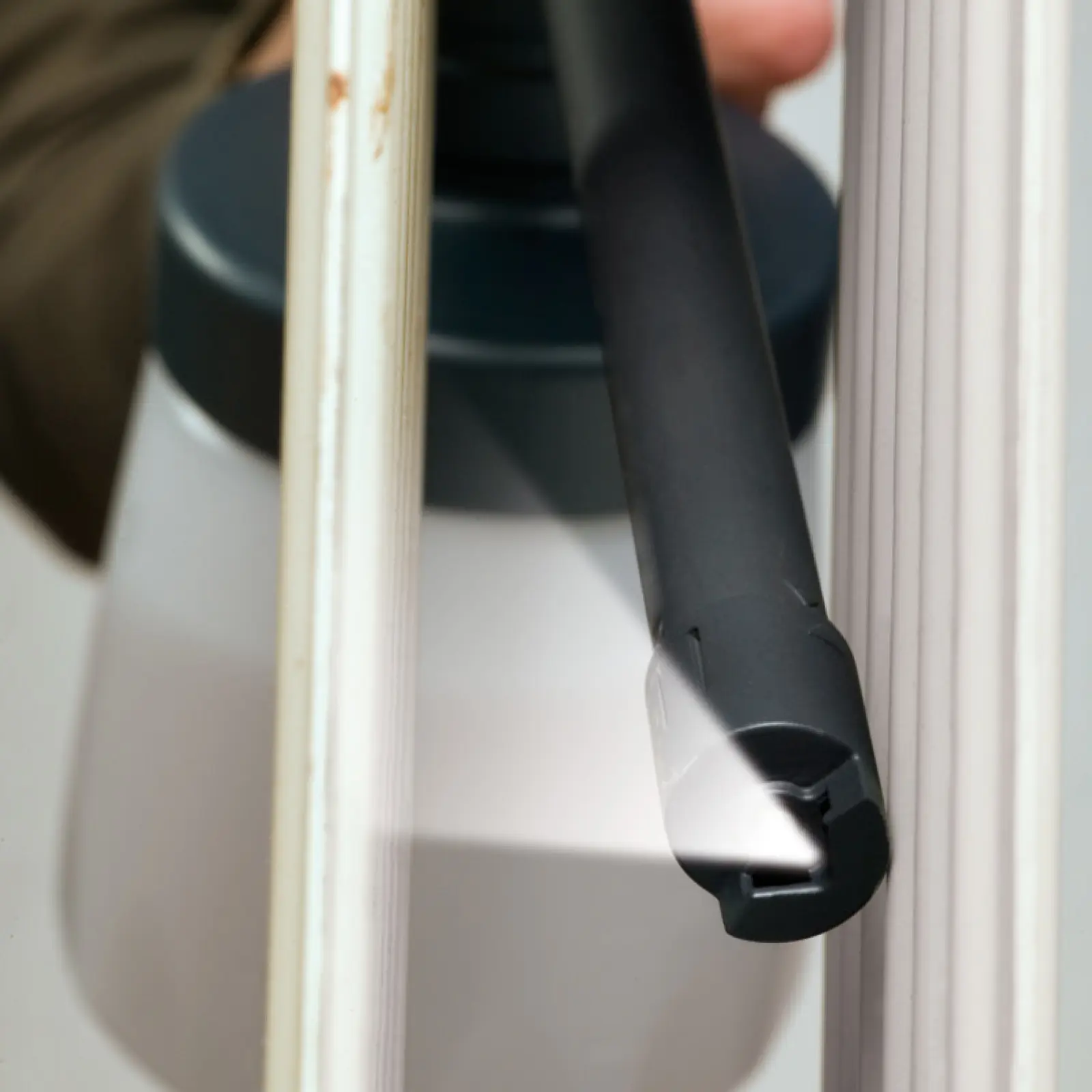 A black spray wand applying a fine white mist.