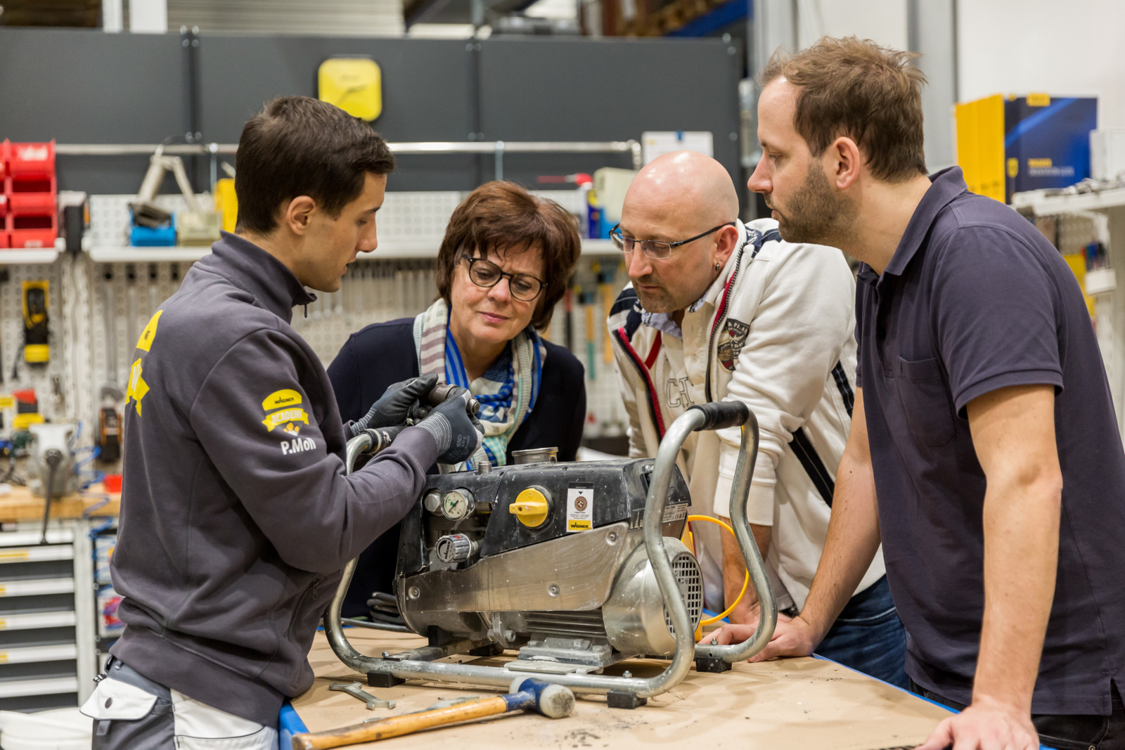 Group learning about machinery maintenance in a workshop setting.