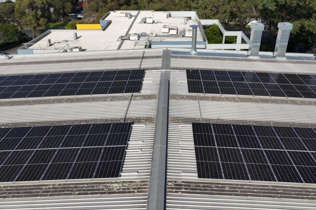 Solar panels on a large industrial building's corrugated metal roof.