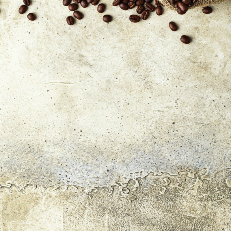 Roasted coffee beans scattered on a light textured background.